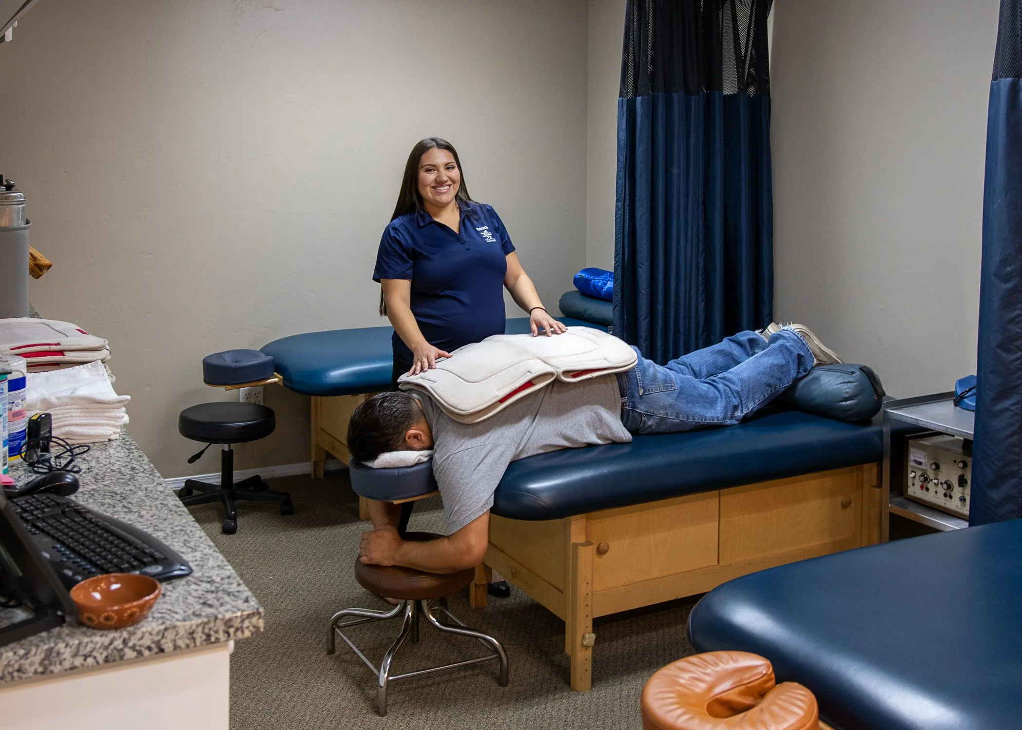 Chiropractor performing spinal examination on patient lying face down on treatment table