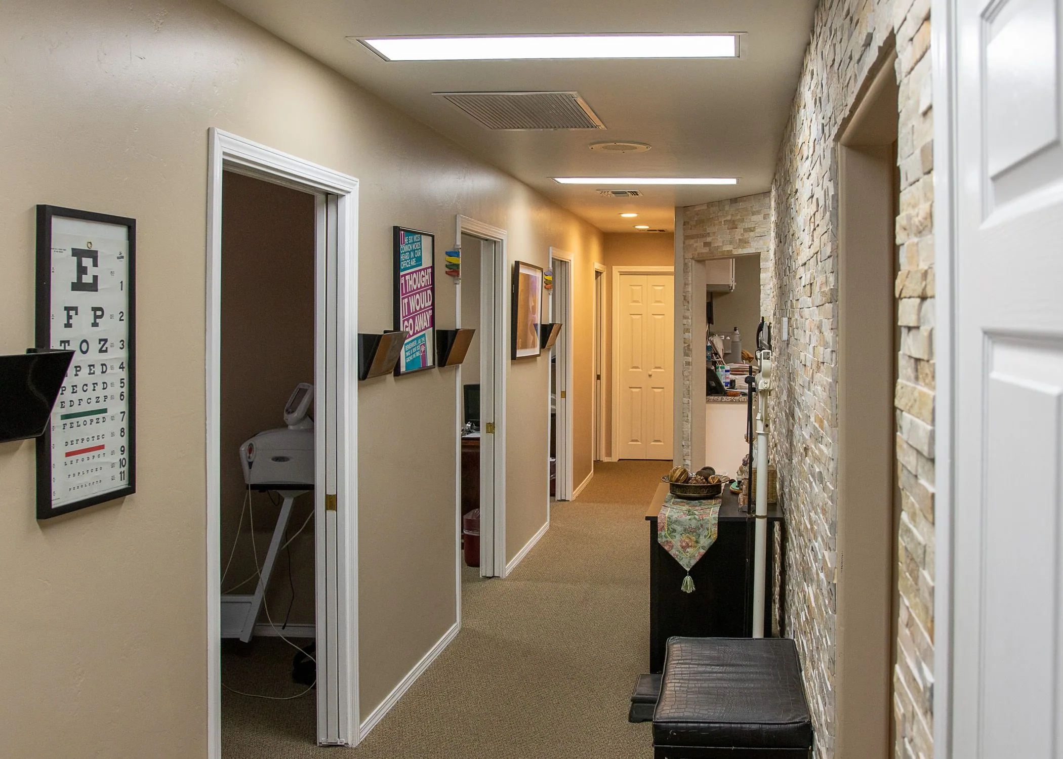 Clinical hallway with examination rooms, eye chart on wall, and waiting area at Haynes Chiropractic
